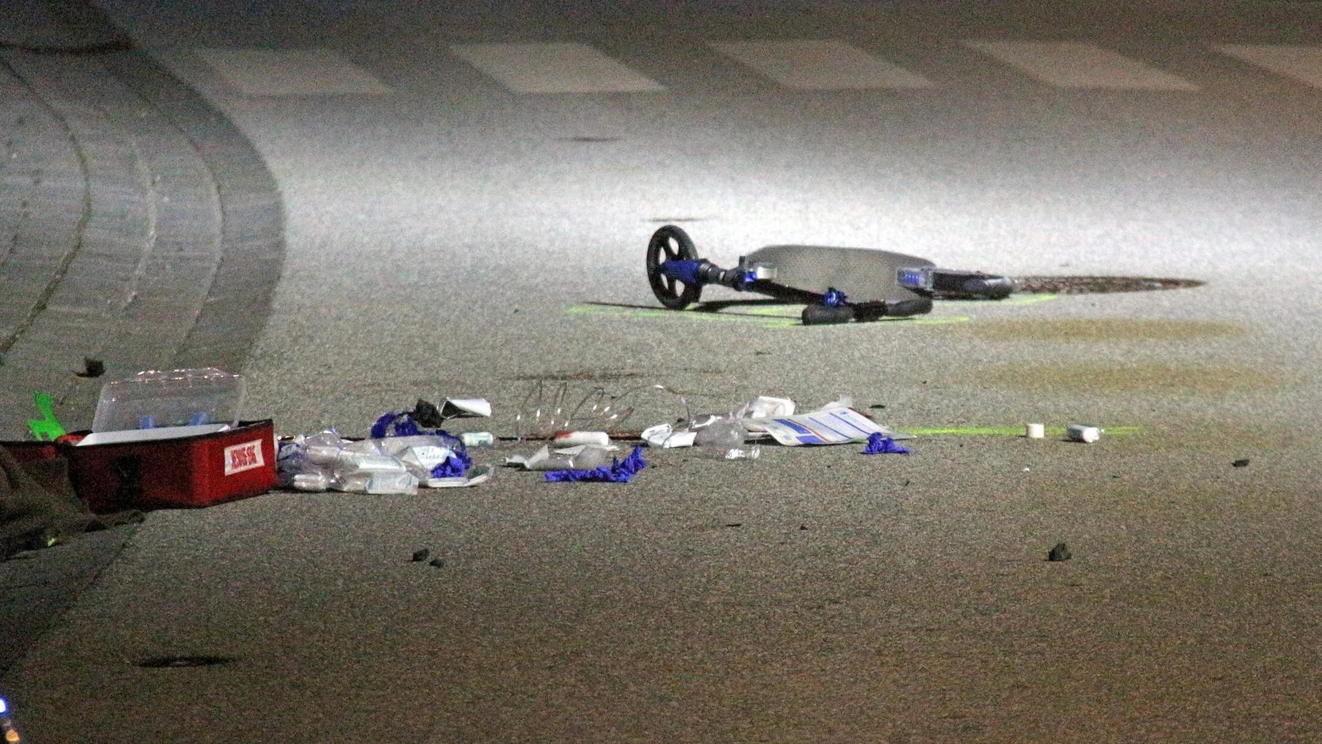 Verbandsmaterial liegt auf der Straße neben einem Tretroller kurz hinter einem Zebrastreifen: Der siebenjährige Junge war mehrere Meter von dem Auto mitgeschleift worden.