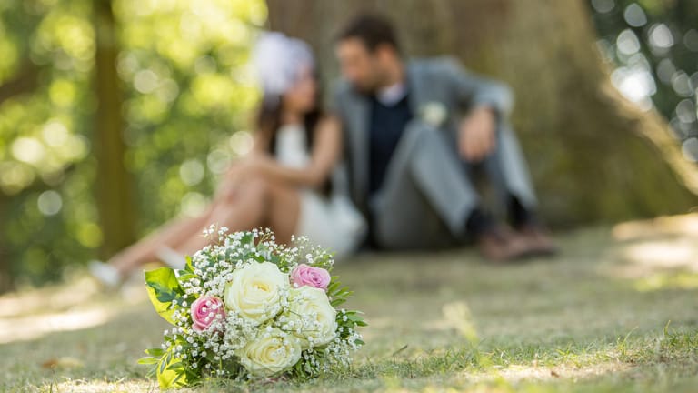 Ein Hochzeitspaar im Park (Symbolbild): Wer ohne Ehevertrag heiratet, lebt automatisch in einer Zugewinngemeinschaft.