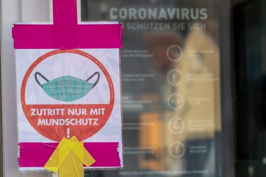 Ein Hinweisschild zeigt am Eingang eines Restaurants, dass der Zutritt nur mit Mund-Nasen-Schutz erlaubt ist.