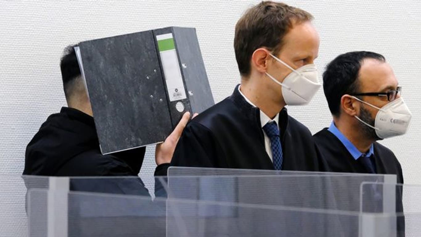 Der Angeklagte verbirgt im Sitzungssaal des Landgerichts Ingolstadt sein Gesicht hinter einem Aktenordner.