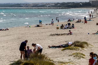 Menschen am Strand von Mallorca: Die Auflagen auf der beliebten Urlaubsinsel sind strenger als in Deutschland.