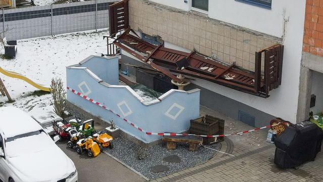 Ein abgestürzter Balkon hängt senkrecht an einer Hauswand. Ein abgestürzter Balkon hängt senkrecht an einer Hauswand.