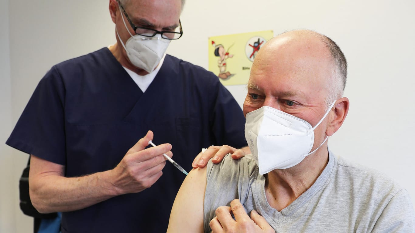 Ein Mann wird vom Hausarzt geimpft (Symbolbild): Laut ersten Rückmeldungen verläuft der Impfstart in Köln noch eher chaotisch.
