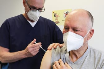 Ein Mann wird vom Hausarzt geimpft (Symbolbild): Laut ersten Rückmeldungen verläuft der Impfstart in Köln noch eher chaotisch.