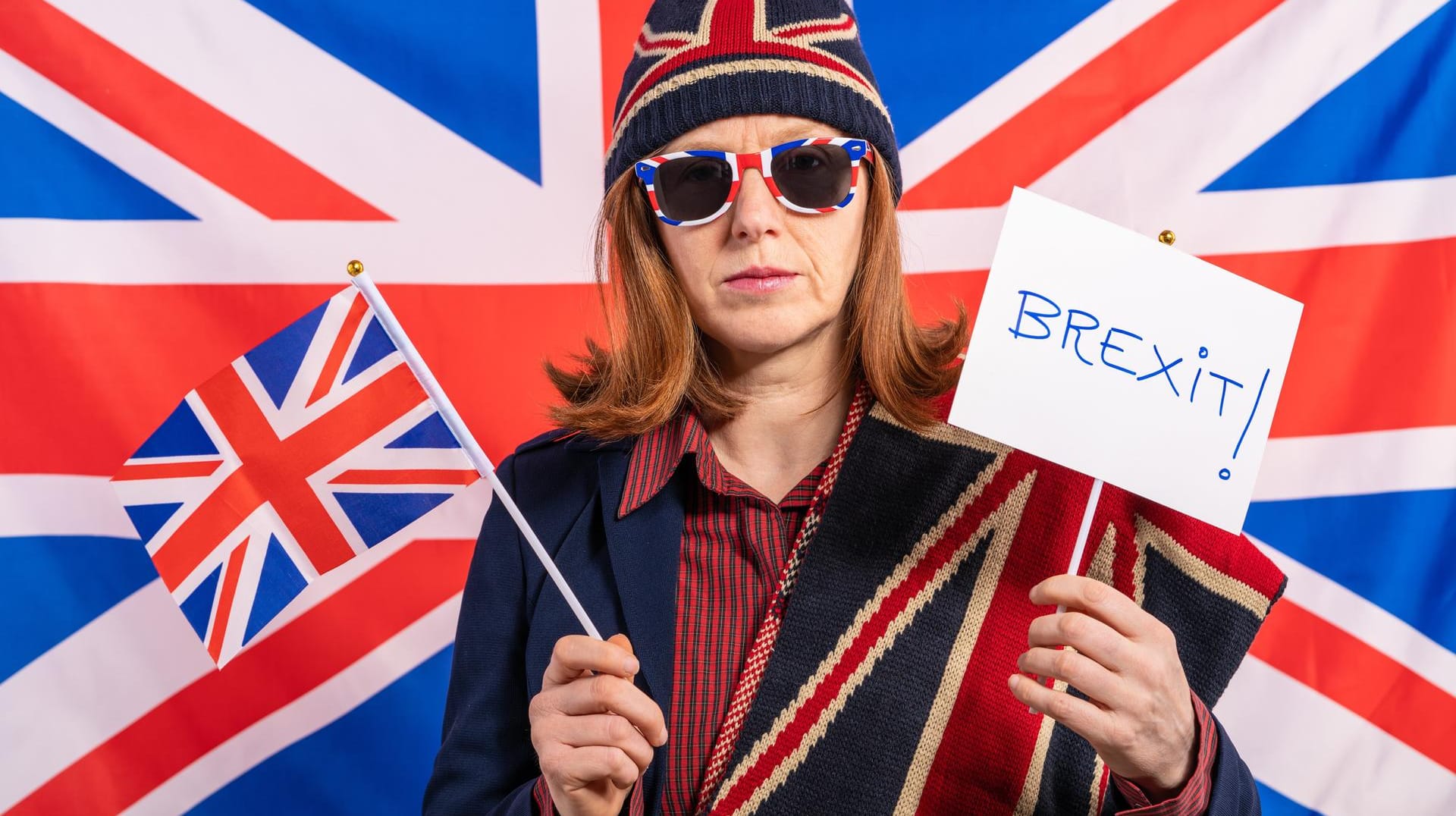 Britin hält vor der Flagge ein Schild mit "Brexit" hoch: Wer hat den Bruch mit der EU besser überstanden? Großbritannien oder die EU?