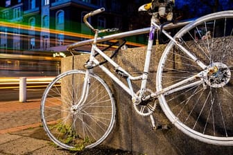 Fahrzeuge fahren an einem sogenannten "Ghost Bike" vorbei, welches an einer Kreuzung in Hannover an einen tödlich verunglückten Fahrradfahrer erinnert.