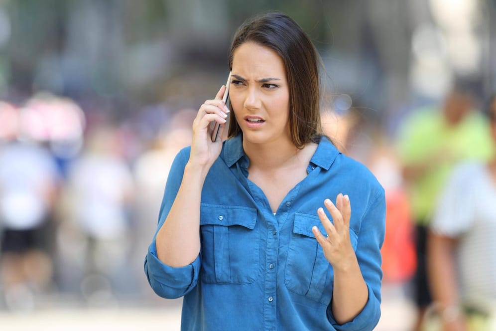 Eine genervte Frau am Telefon: Vorsicht vor Telefonbetrügern.