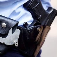 Ein Polizist mit Handschellen und Pistole am Gürtel (Symbolbild): Mehr als 3.000 Hamburger Strafbefehle sind nicht vollstreckt worden.