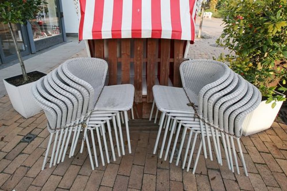 Zusammengestellte Stühle und ein geschlossener Strandkorb stehen vor einem Gastronomiebetrieb (Symbolbild): Ab Montag darf die Gastronomie ihre Außenbereiche wieder öffnen.
