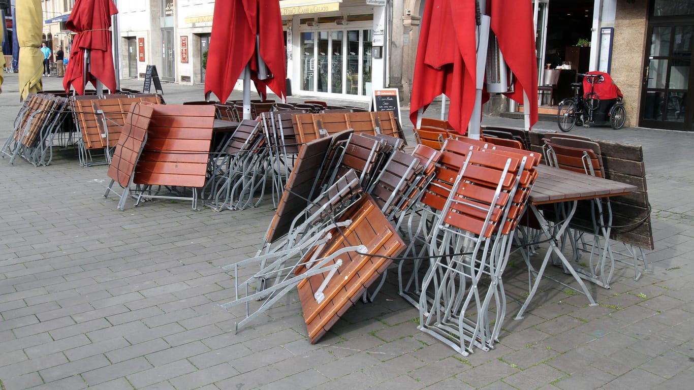 Zusammengeräumte Tische und Stühle stehen am Alter Markt in der Altstadt von Köln: Die Stadt wurde als NRW-Modellkommune ausgewählt.