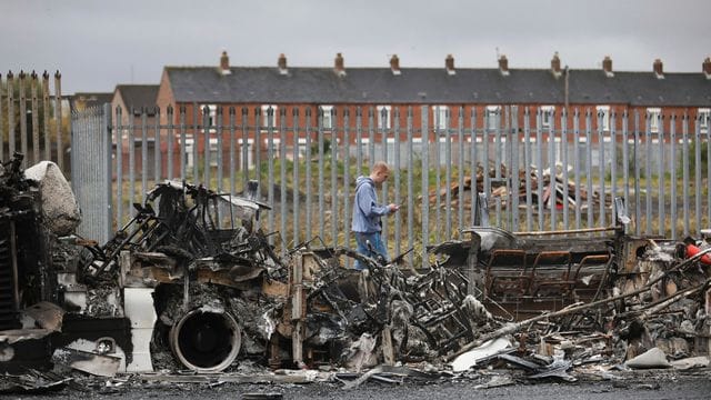 Ein Mann geht an einem ausgebrannten Bus auf der Shankill Road in West Belfast vorbei. Ein Mann geht an einem ausgebrannten Bus auf der Shankill Road in West Belfast vorbei.