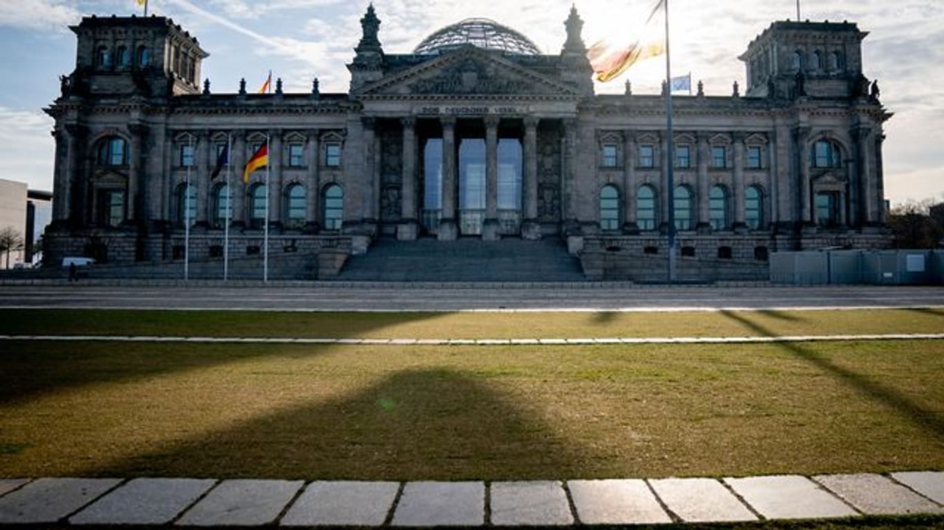 Die Sonne steht am Morgen hinter dem Reichstagsgebäude mit dem Bundestag.
