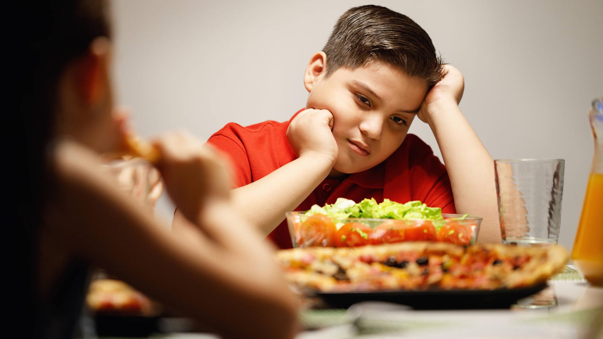 Ein trauriges Kind sitzt vor dem Essen (Symbolbild): Die Corona-Pandemie hat laut Experten massive Auswirkungen auf Kinder.