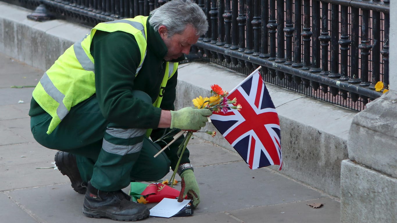 Großbritannien, London: Ein Arbeiter räumt vor dem Buckingham Palace die zu Ehren des britischen Prinz Philip, Herzog von Edinburgh, hinterlassenen Tribute weg.