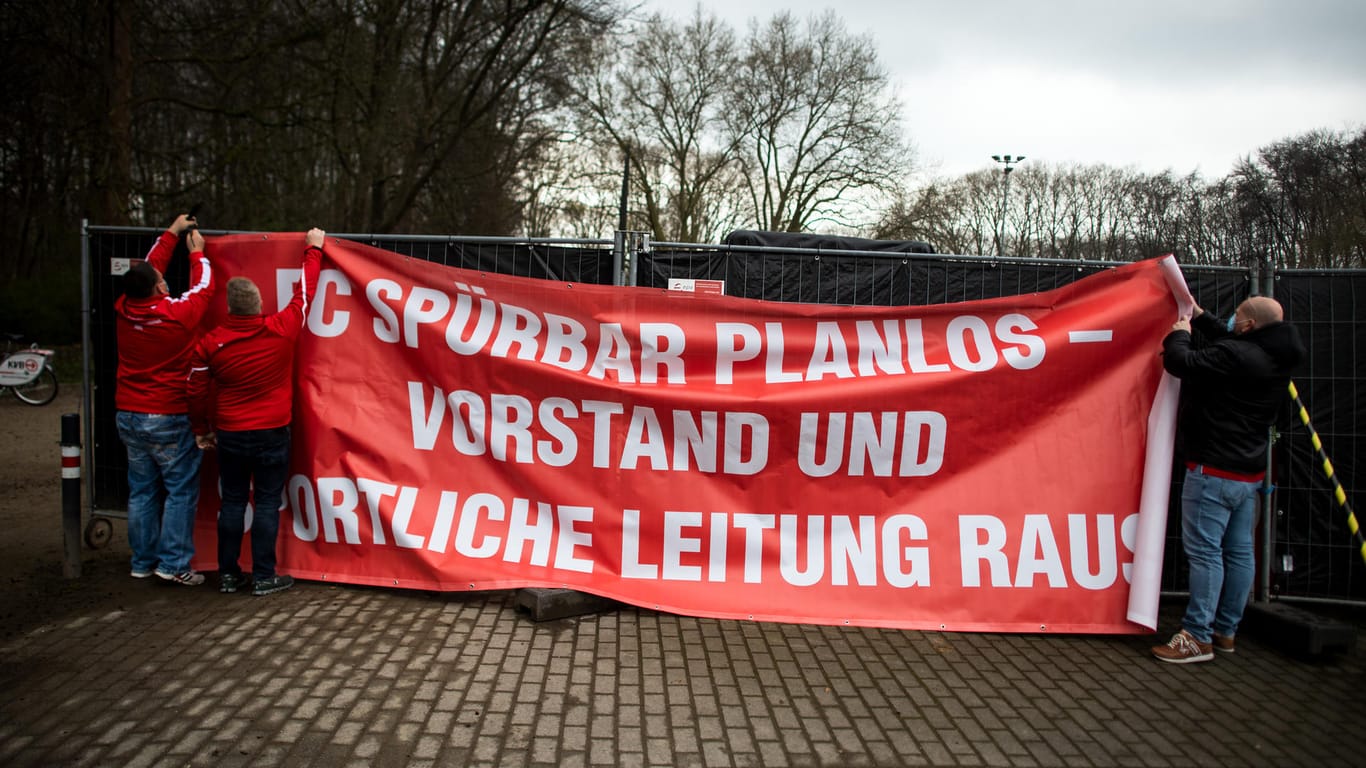 FC Köln-Fans hängen ein Protestplakat mit der Aufschrift "FC SPÜRBAR PLANLOS – VORSTAND UND SPORTLICHE LEITUNG RAUS" auf: Die Fans des Klubs zeigen ihren Unmut über die aktuelle Situation.