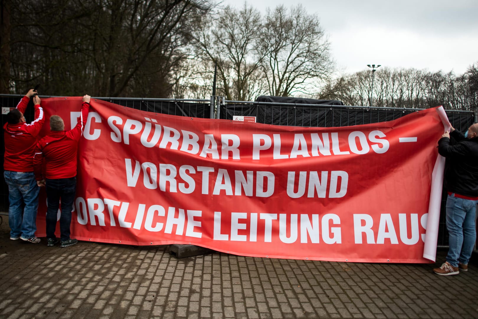 FC Köln-Fans hängen ein Protestplakat mit der Aufschrift "FC SPÜRBAR PLANLOS – VORSTAND UND SPORTLICHE LEITUNG RAUS" auf: Die Fans des Klubs zeigen ihren Unmut über die aktuelle Situation.