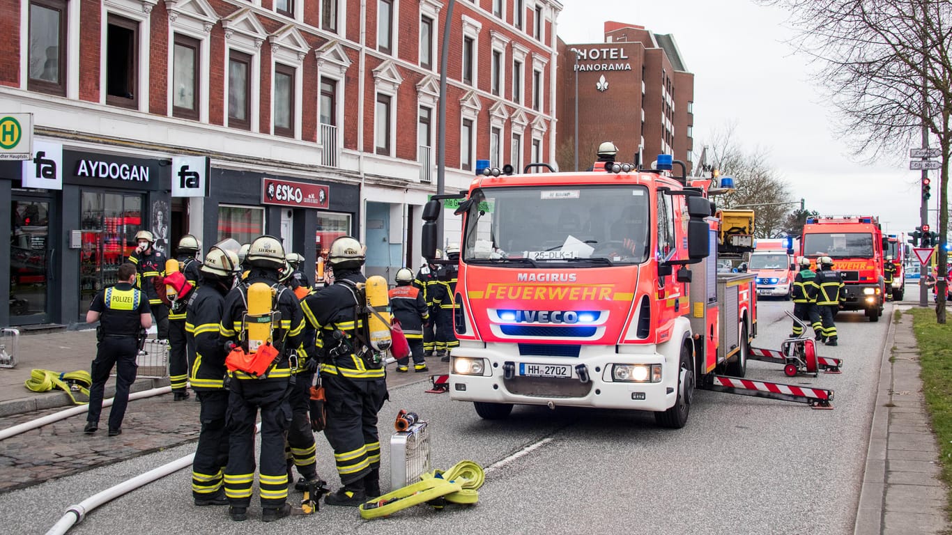 Hamburg: Feuerwehrleute stehen im Stadtteil Billstedt vor einer brennenden Wohnung. Bei dem Brand sind mehrere Menschen verletzt worden.