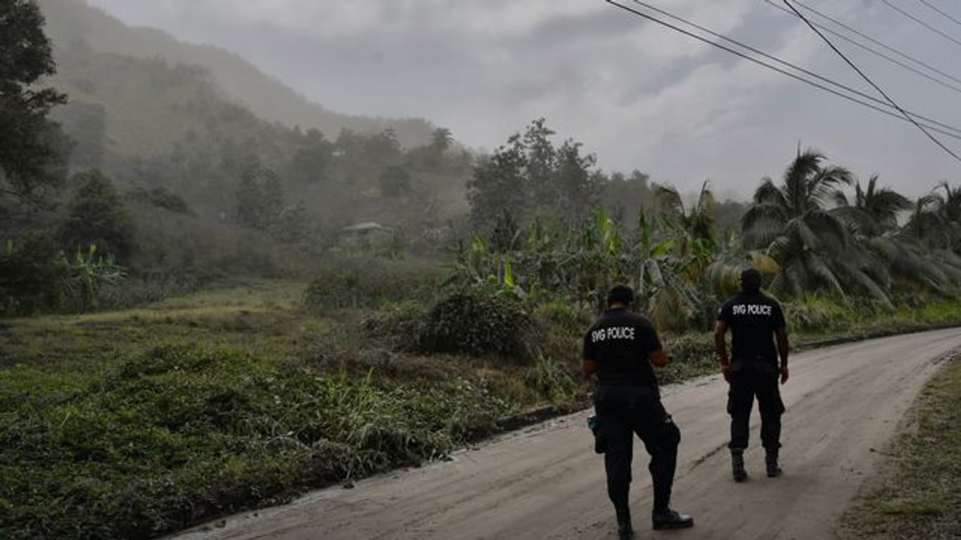 Polizisten patrouillieren auf einer aschebedeckten Straße auf der Karibikinsel St.