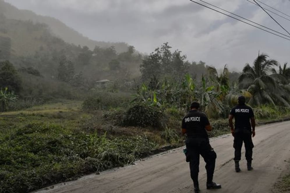 Polizisten patrouillieren auf einer aschebedeckten Straße auf der Karibikinsel St.