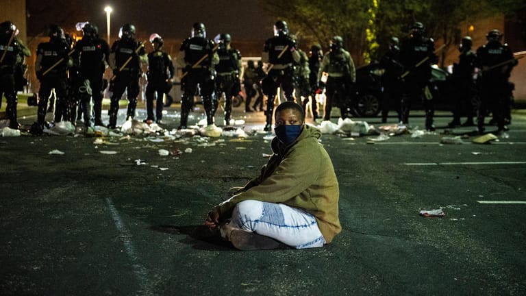 Ein Demonstrant sitzt auf einer Straße vor einer Reihe von Bereitschaftspolizisten: In den USA hat ein neuer Fall von Polizeigewalt heftige Proteste ausgelöst.