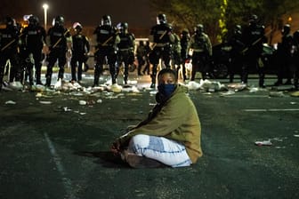 Ein Demonstrant sitzt auf einer Straße vor einer Reihe von Bereitschaftspolizisten: In den USA hat ein neuer Fall von Polizeigewalt heftige Proteste ausgelöst.