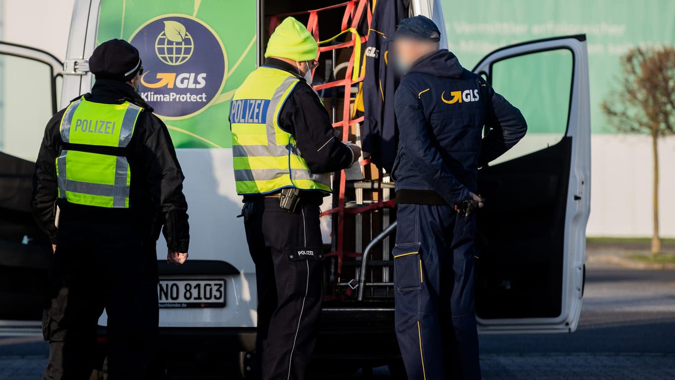 Polizisten und Zollbeamte inspizieren einen Fahrer und dessen Auslieferungfahrzeug: Am Dienstag kontrolliert der Zoll die Arbeitsbedingungen von Paketwagenfahrern im Raum Köln/Bonn.