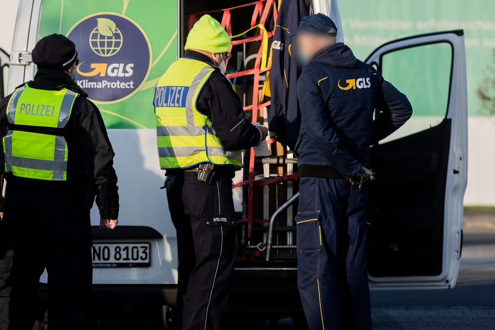 Polizisten und Zollbeamte inspizieren einen Fahrer und dessen Auslieferungfahrzeug: Am Dienstag kontrolliert der Zoll die Arbeitsbedingungen von Paketwagenfahrern im Raum Köln/Bonn.