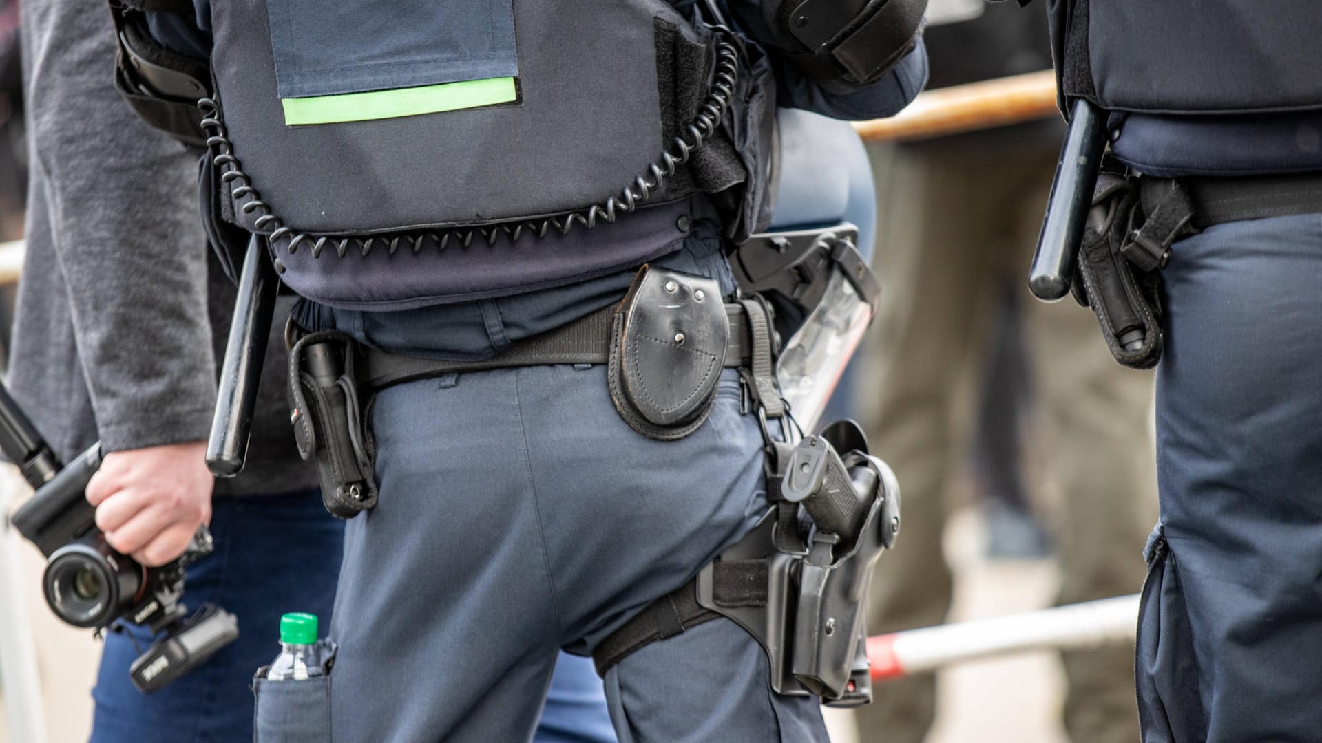 Ein Polizist trägt einen Helm und seine Schutzausrütung am Gürtel (Symbolbild): Bei einer Demonstation gegen einen Querdenker-Marsch ist es zu Ausschreitungen gekommen.