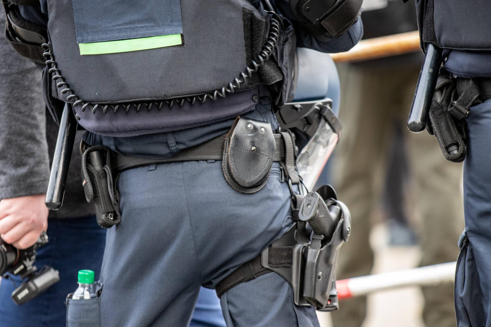 Ein Polizist trägt einen Helm und seine Schutzausrütung am Gürtel (Symbolbild): Bei einer Demonstation gegen einen Querdenker-Marsch ist es zu Ausschreitungen gekommen.