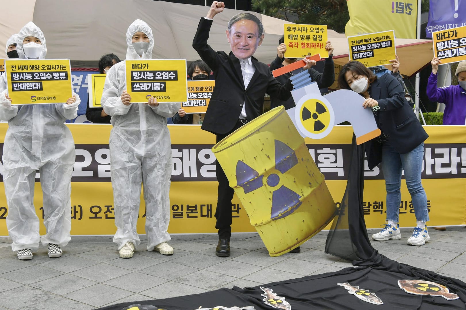Menschen protestieren mit Schildern und Masken: Der Protest richtet sich gegen Pläne des Kraftwerksbetreibers Tepco.