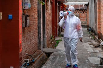 Die chinesische Stadt Ruili: Ein Mitarbeiter des Gesundheitswesens ruft in ein Megafon und informiert Anwohner über die Durchführung eines Corona-Nukleinsäuretests.
