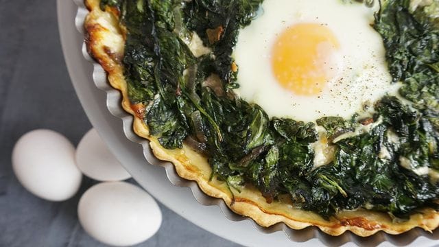 Die Tarte mit der Spinat-Masse und ausgesparten Mulden wird zunächst 20 Minuten gebacken.