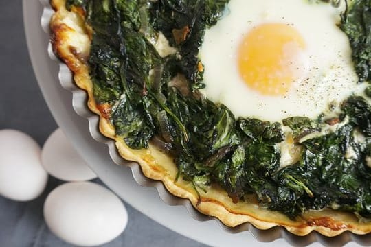 Die Tarte mit der Spinat-Masse und ausgesparten Mulden wird zunächst 20 Minuten gebacken.