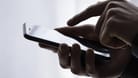 Eine Hand tippt auf einem Smartphone (Symbolbild): Experten befürchten eine Welle von Betrugs-SMS, sogenanntem "Smishing".