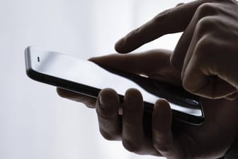 Eine Hand tippt auf einem Smartphone (Symbolbild): Experten befürchten eine Welle von Betrugs-SMS, sogenanntem "Smishing".