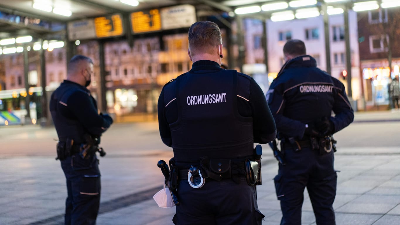 Drei Mitarbeiter des Ordnungsamts stehen auf dem Hagener Bahnhofsvorplatz (Symbolbild): In der Stadt gilt eine Ausgangssperre von 21 bis 5 Uhr.