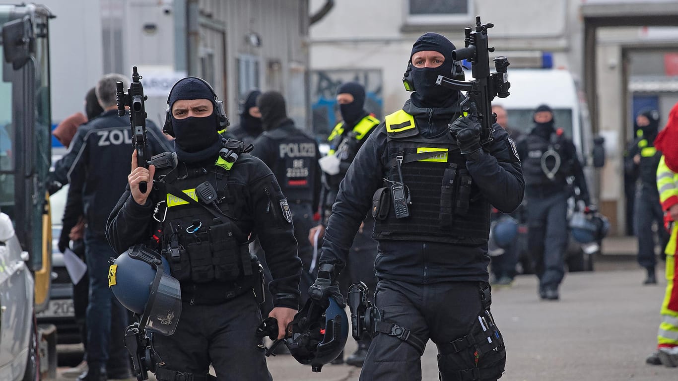 Einsatzkräfte der Polizei gehen mit ihren Waffen in der Hand über ein Gelände in Lichtenberg: Mit einer Razzia gingen die Beamten gegen mutmaßliche, international operierende Drogenhändler vor.