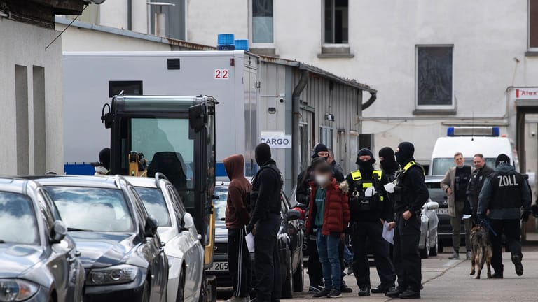 Einsatzkräfte der Polizei stehen auf einem Gelände in Lichtenberg neben festgenommenen Personen: Hunderte Beamte waren im Einsatz.