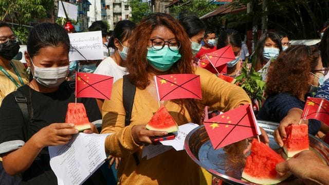 Anti-Putsch-Demonstranten tragen während eines Protests Wassermelonenstücke, in denen durchgestrichene chinesische Fähnchen stecken. Anti-Putsch-Demonstranten tragen während eines Protests Wassermelonenstücke, in denen durchgestrichene chinesische Fähnchen stecken.