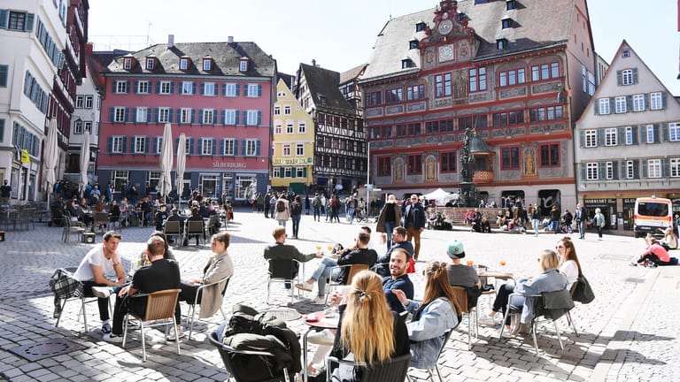Tübingen Ende März: Bei sonnigem Wetter sitzen Gäste in einem Café auf dem Marktplatz.