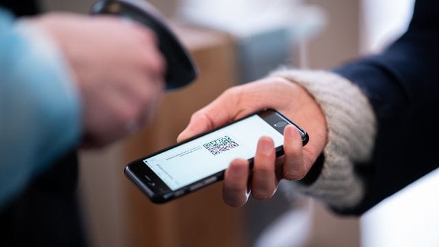Eine Frau lässt am Eingang eines Corona-Schnelltest-Zentrums einen QR-Code auf ihrem Smartphone abscannen. Eine Frau lässt am Eingang eines Corona-Schnelltest-Zentrums einen QR-Code auf ihrem Smartphone abscannen.