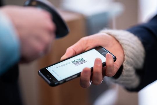 Eine Frau lässt am Eingang eines Corona-Schnelltest-Zentrums einen QR-Code auf ihrem Smartphone abscannen.
