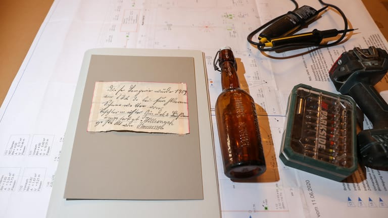 Eine 112 Jahre alte Flaschenpost liegt auf Bauplänen im Alten Rathaus: Die Flasche ist bei Bauarbeiten hinter einer Holzvertäfelung gefunden worden.