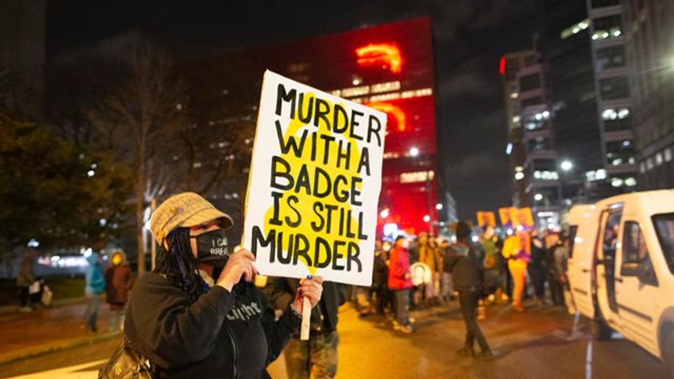 Eine Frau hält während eines Protests in Minneapolis ein Schild mit der Aufschrift "Murder with a badge is still murder" ("Mord mit einer Dienstmarke ist immer noch Mord").
