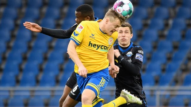 Braunschweigs Felix Kroos (M) kommt gegen Aristote Nkaka (l) und Ron Schallenberg vom SC Paderborn zum Kopfball.