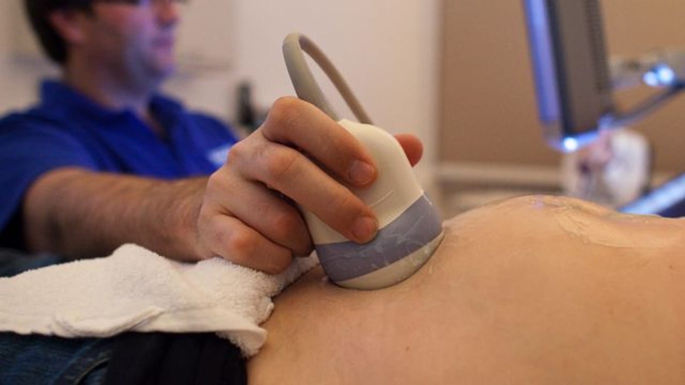 Ein Facharzt für Gynäkologie und Geburtshilfe untersucht in seiner Praxis für pränatale Diagnostik und Ultraschall eine schwangere Frau.