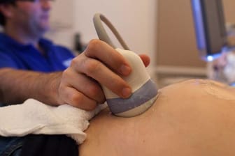 Ein Facharzt für Gynäkologie und Geburtshilfe untersucht in seiner Praxis für pränatale Diagnostik und Ultraschall eine schwangere Frau.