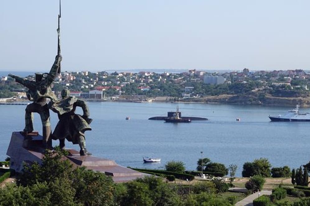 Hinter einem sowjetischen Denkmal liegen ein U-Boot und Kriegsschiffe der russischen Schwarzmeerflotte vor Anker in der Hafenstadt Sewastopol.