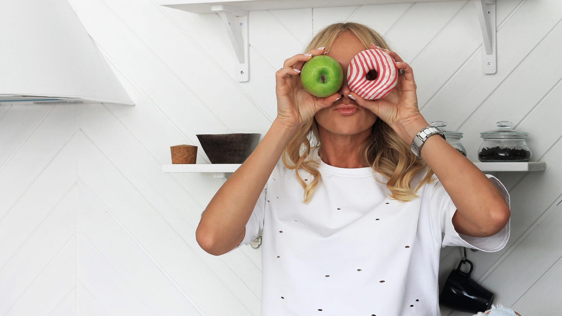 Frau hält einen Apfel und einen Donut in der Hand