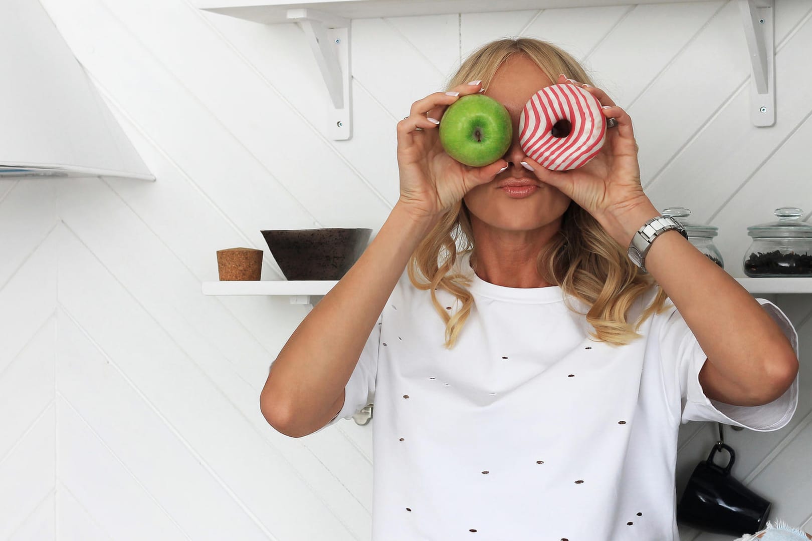 Frau hält einen Apfel und einen Donut in der Hand